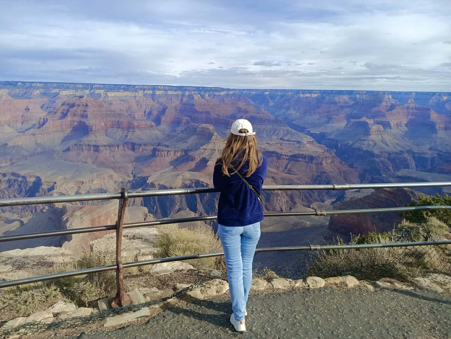 Standing at the railing on the rim of the Grand Canyon, looking out over the layered red rock.